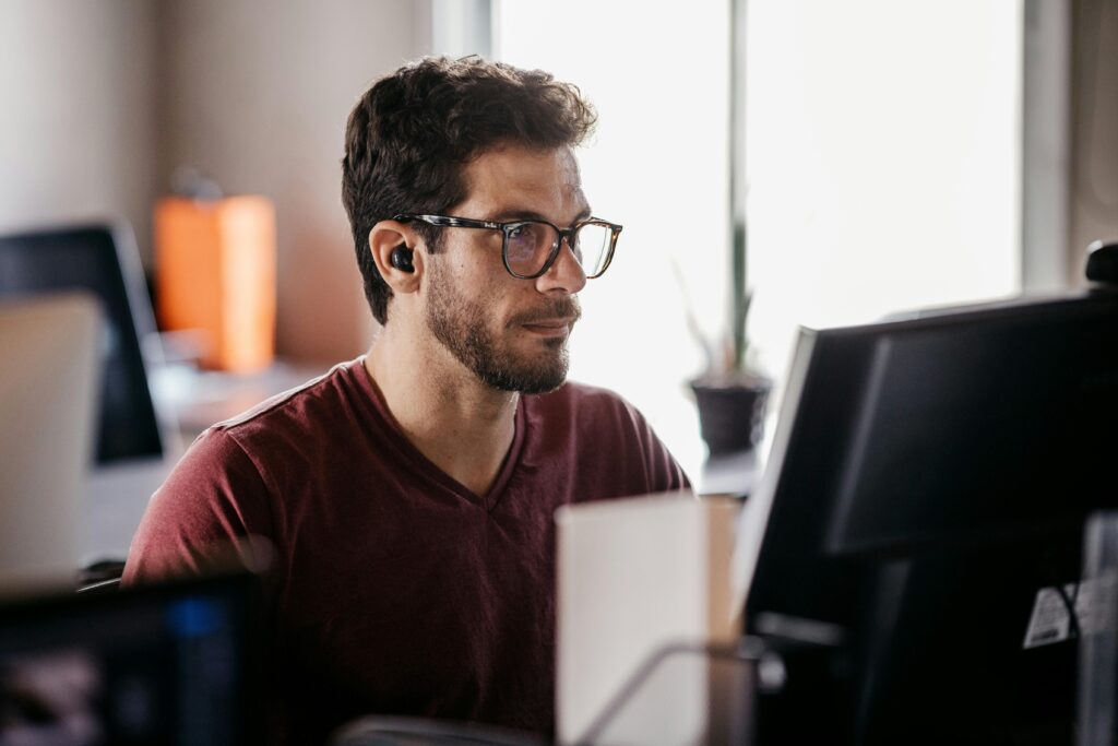 Man in eyeglasses concentrating on computer screen in modern office